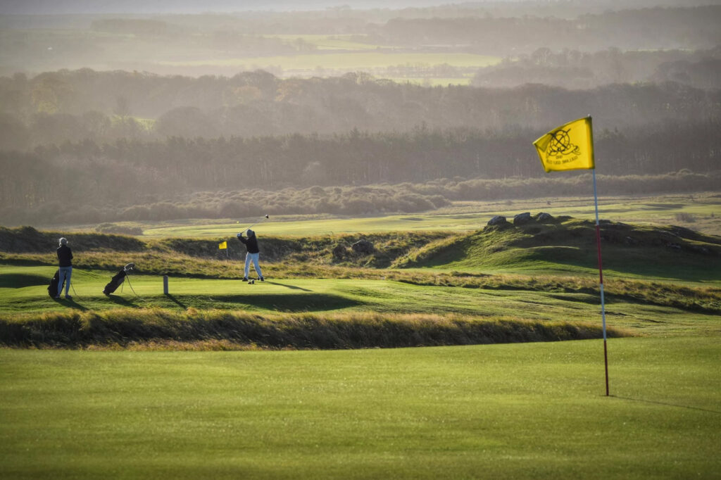 People playing golf at Gullane Golf Club – No. 3 Course with yellow flag in foreground