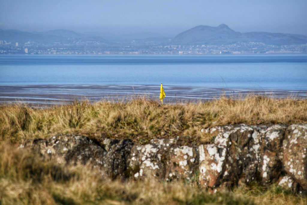 Yellow flag with ocean in background at Gullane Golf Club – No. 3 Course