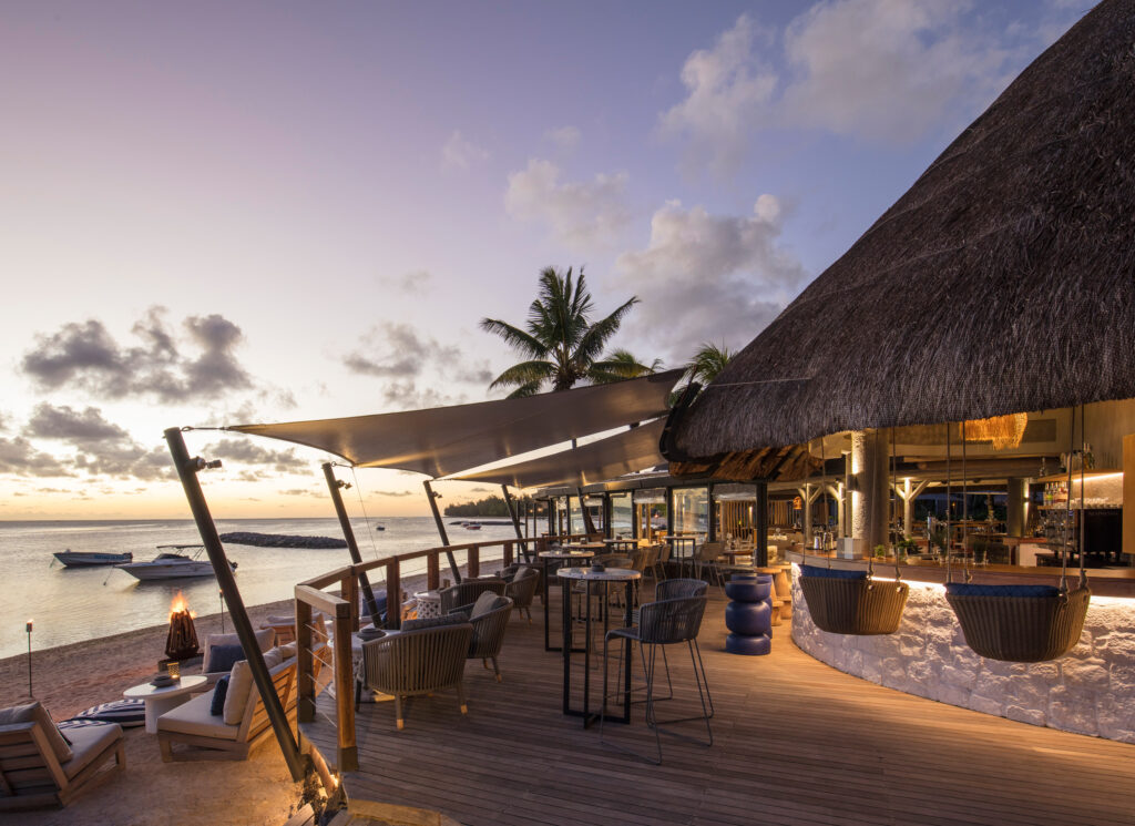 Outdoor bar area at Heritage Awali Golf and Spa Resort on the beach at sunset