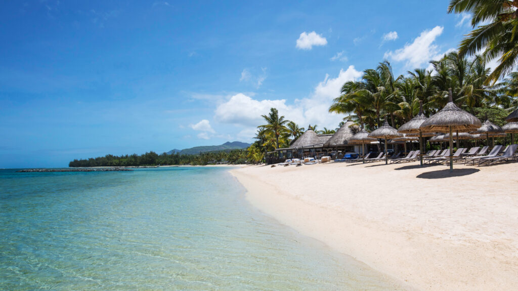 Beach with sun loungers and straw umbrellas at Heritage Awali Golf and Spa Resort