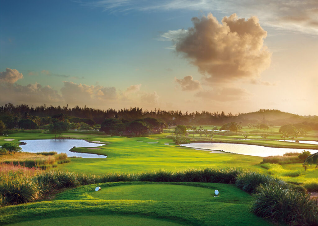 Tee box overlooking fairway with lakes and trees around at Heritage Golf Club - Le Chateau Course at sunset