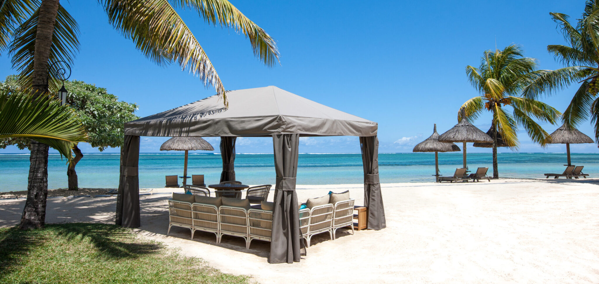 Sun loungers on beach at Heritage Le Telfair with palm trees