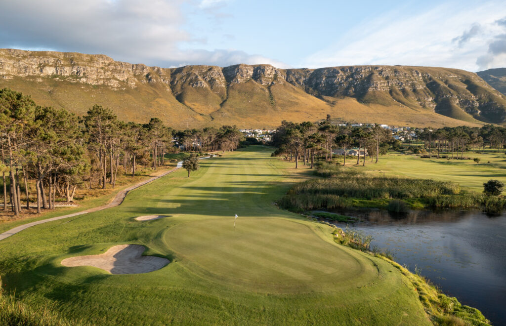 Aerial view of hole at Hermanus Golf Club with mountains and trees in distance