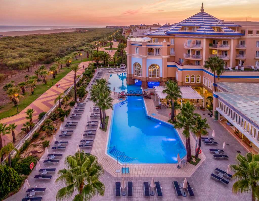 Exterior of Hotel Melia Isla Canela with outdoor pool at sunset