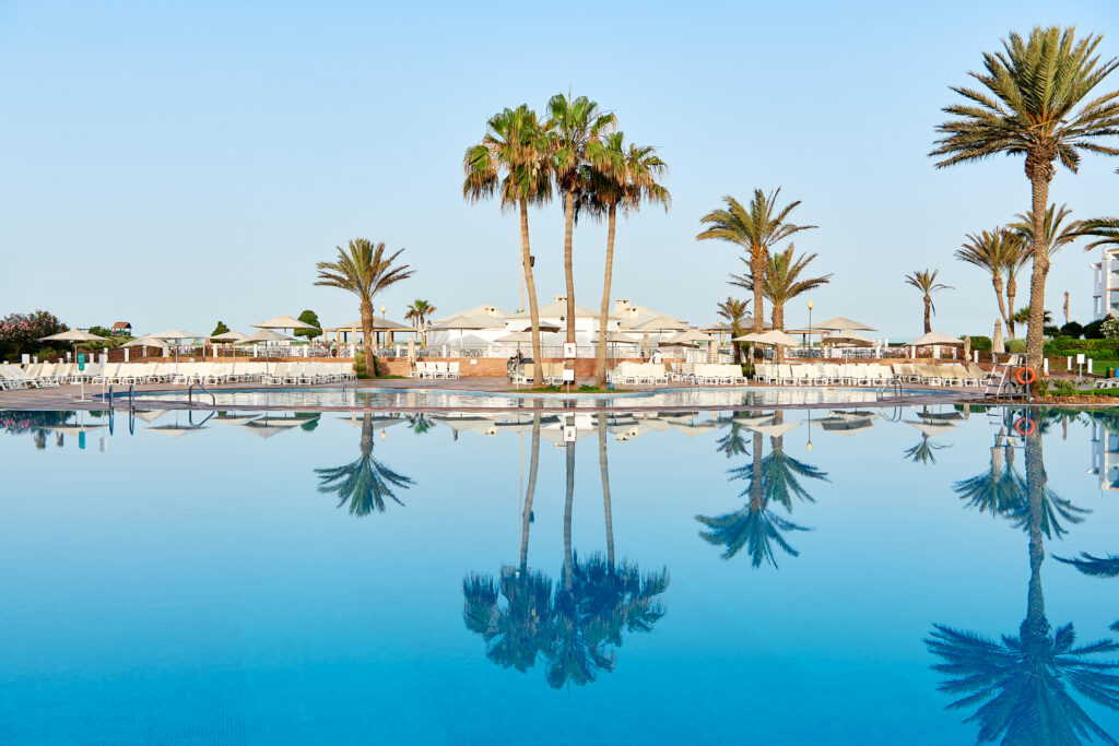 Outdoor pool with loungers and palm trees at Iberostar Founty Beach Hotel