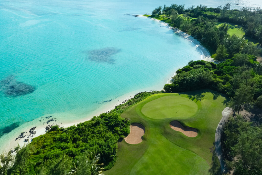 Aerial view of a hole with bunkers at Ile Aux Cerfs Golf Club with ocean view and trees around