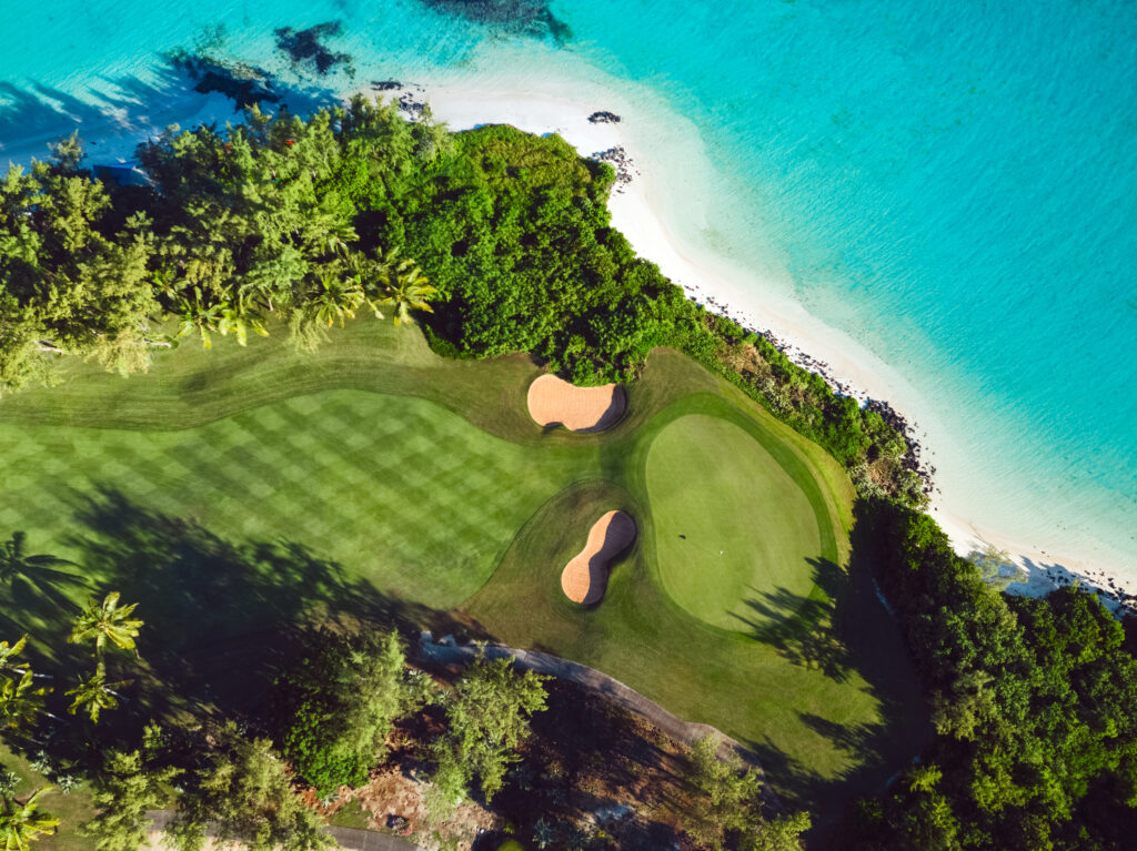 Aerial view of a hole with bunkers at Ile Aux Cerfs Golf Club with beach view and trees around