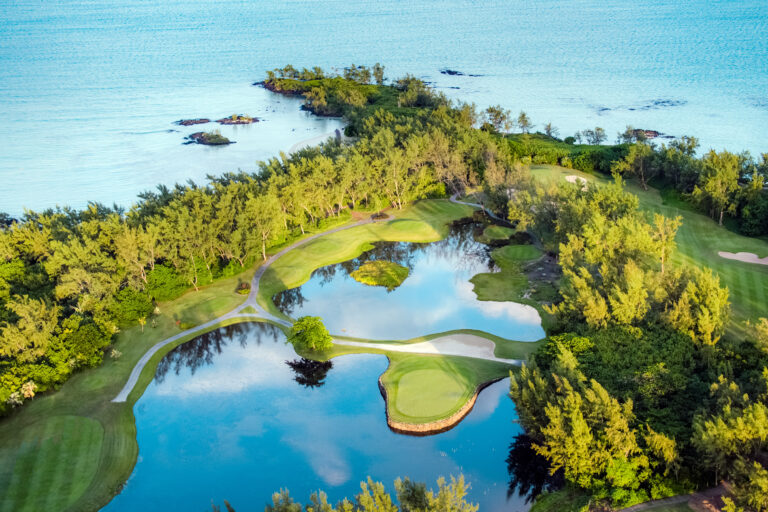 Lakes on fairway with trees around with ocean in background at Ile Aux Cerfs Golf Club