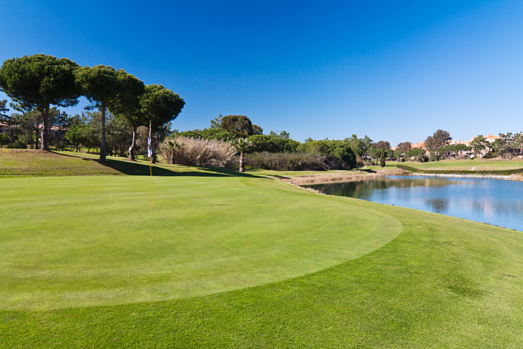 A hole with a lake and trees in background at Islantilla Golf Course