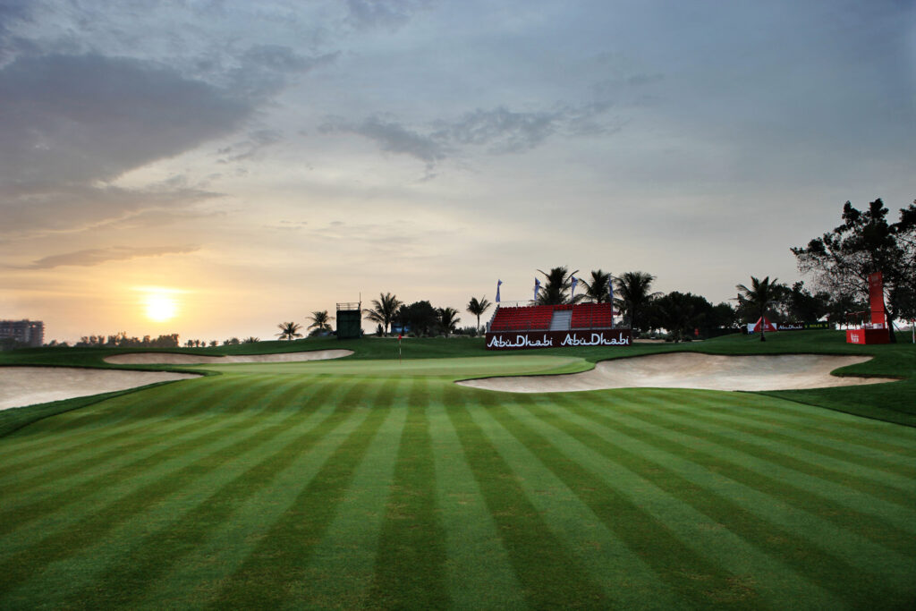 Hole with bunkers at Abu Dhabi Golf Club - National with stadium seating in background