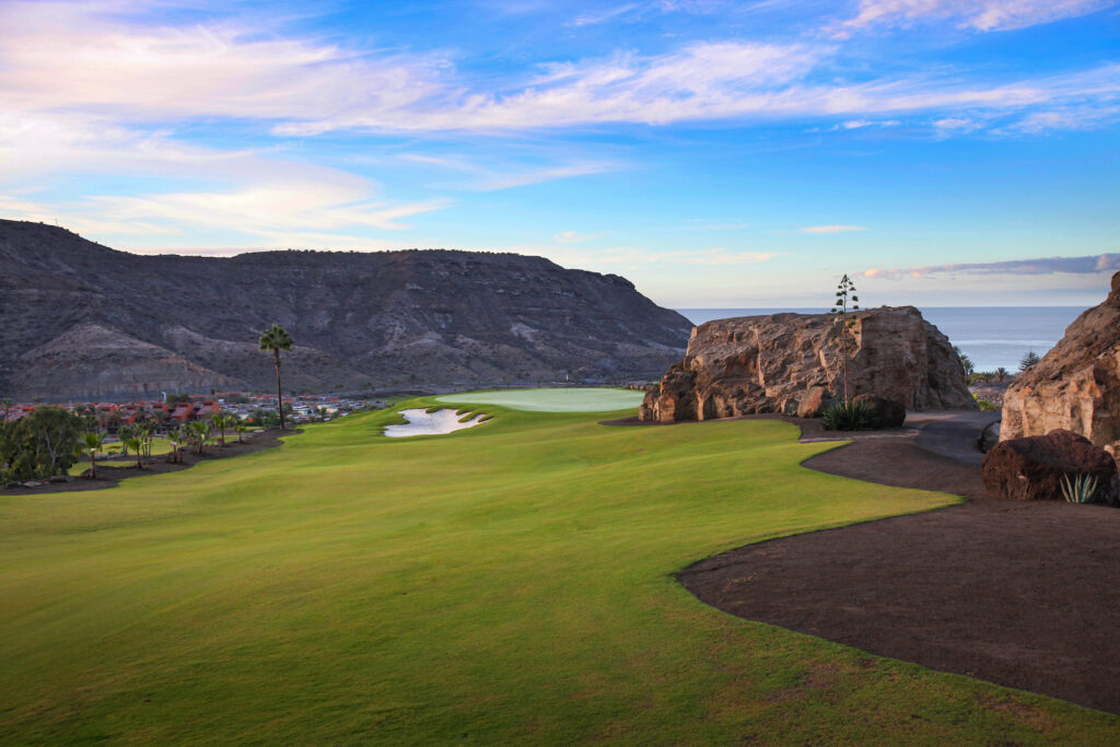 Fairway with bunker and trees around at Anfi Tauro with hillsides in view