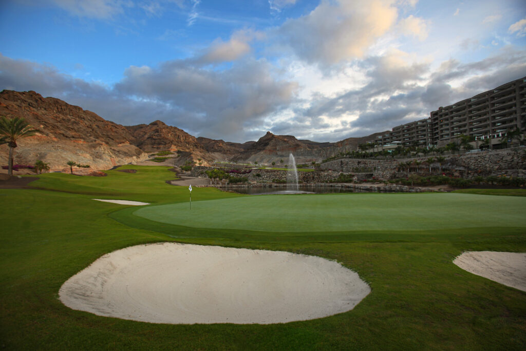 Hole with bunkers and hillsides with building in background at Anfi Tauro