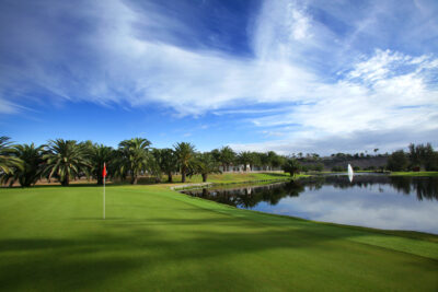 Hole with lake atCampo de Golf de Maspalomas with trees in background