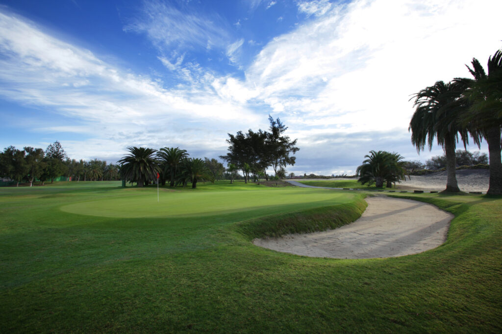 Hole with trees around and a bunker at Campo de Golf de Maspalomas