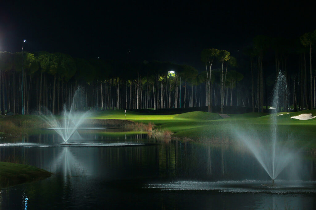 Lake with fountains and fairway with trees around at Carya Golf Course