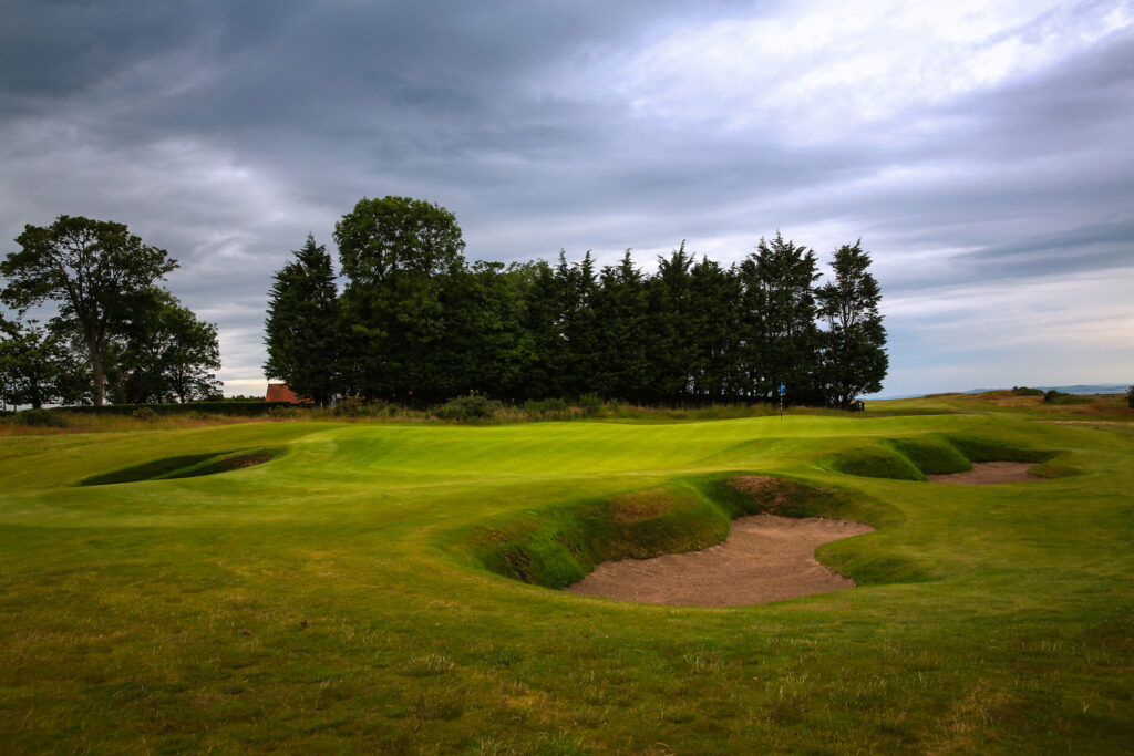 Hole with bunkers at Craigielaw Golf Club with trees in background