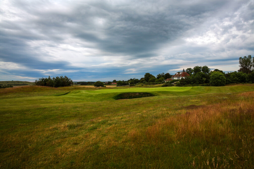 Fairway leading to hole with bunkers at Craigielaw Golf Club with building in distance