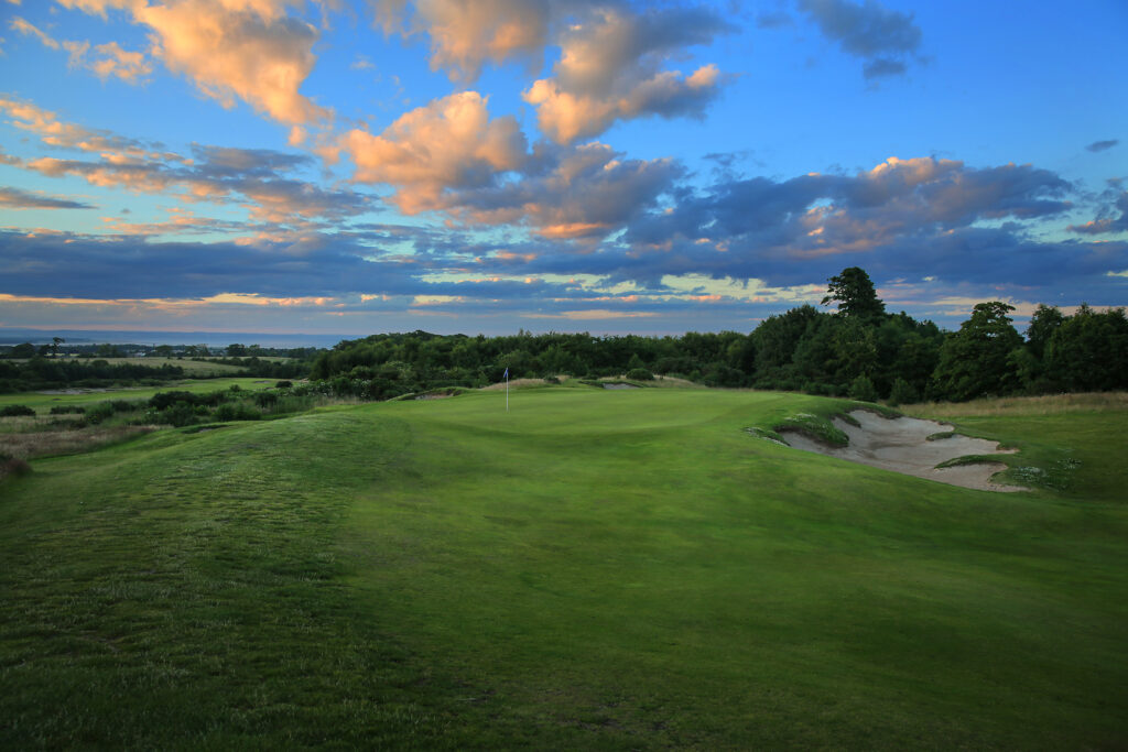 Hole with bunker at The Dukes Course with trees in background