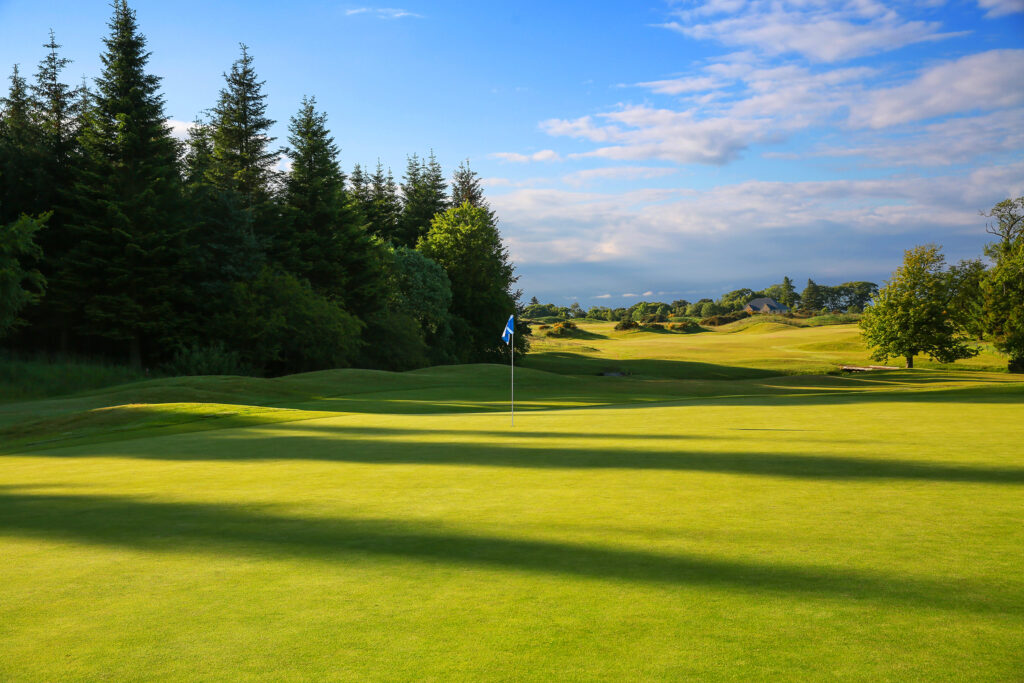 Hole with blue flag at The Dukes Course with trees around