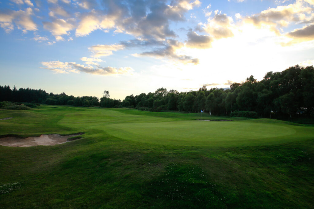 Hole with blue flag and bunkers at The Dukes Course with trees around