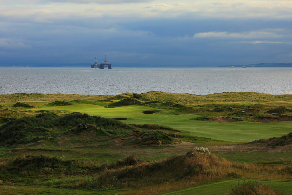 Fairway at Dumbarnie Links leading to hole with bunkers with ocean in background