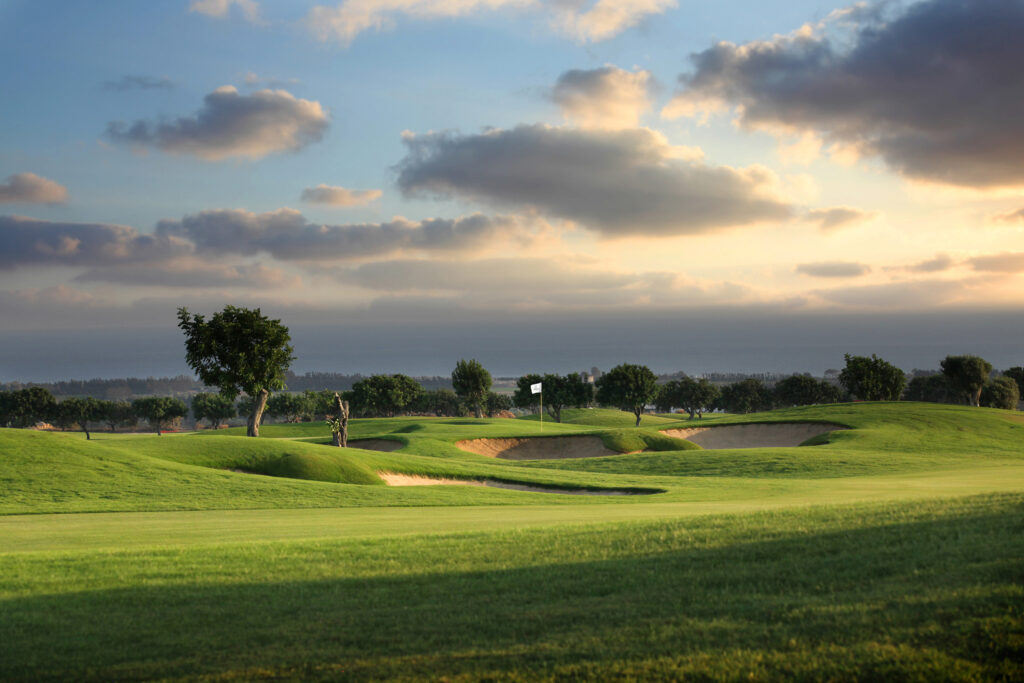 Hole with bunkers at Elea Golf Club with trees in background