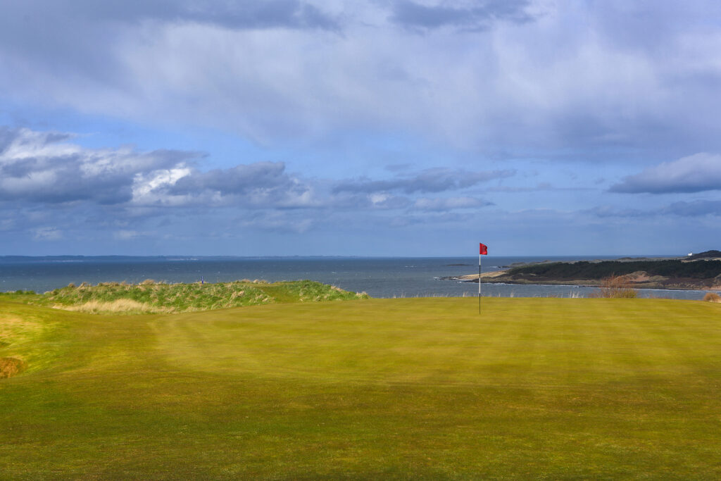 Hole with red flag at Gullane Golf Club - No. 1 Course with ocean view