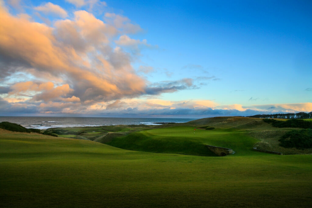 Fairway at Kingsbarns Golf Links leading to hole with red flag with ocean view