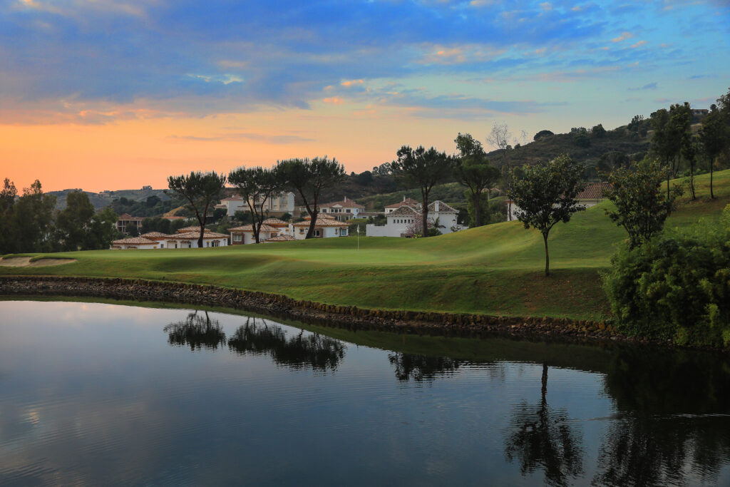 Lake on fairway with trees and buildings in background at sunset at La Cala - Asia Golf Course