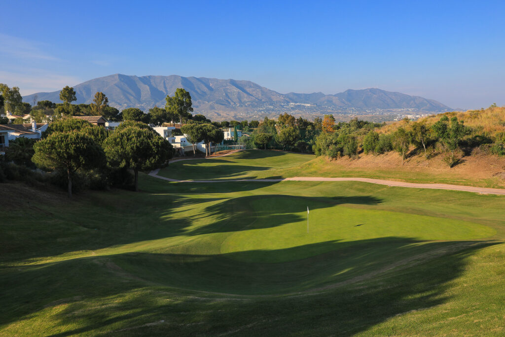 Hole with trees around and hill in background at La Cala - Asia Golf Course