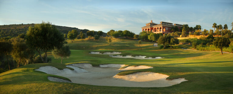 Fairway with bunkers and trees around with building in background at La Reserva de Sotogrande Golf Course