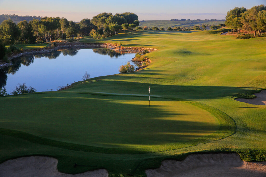 A hole with a white flag at Las Colinas Golf & Country Club with a lake