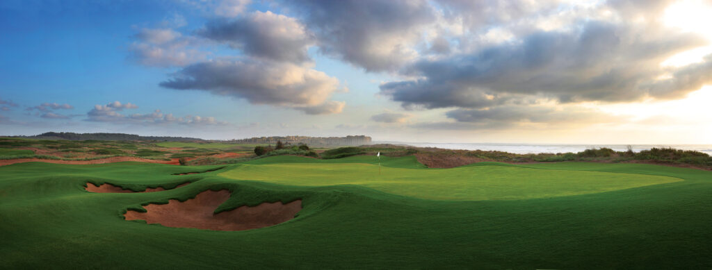 Hole with bunkers at Mazagan Golf Course with buildings in distance