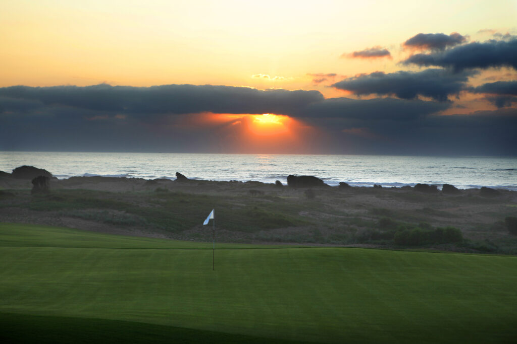 Hole at Mazagan Golf Course with ocean view at sunset