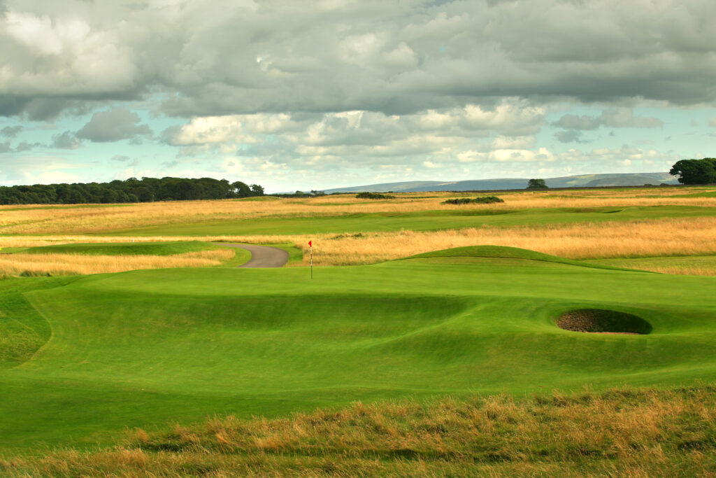 Hole with red flag at Muirfield with fairway in background