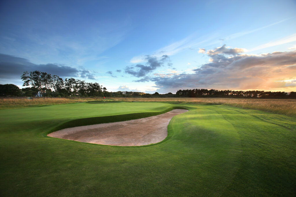 Hole with bunker and trees in distance at Muirfield