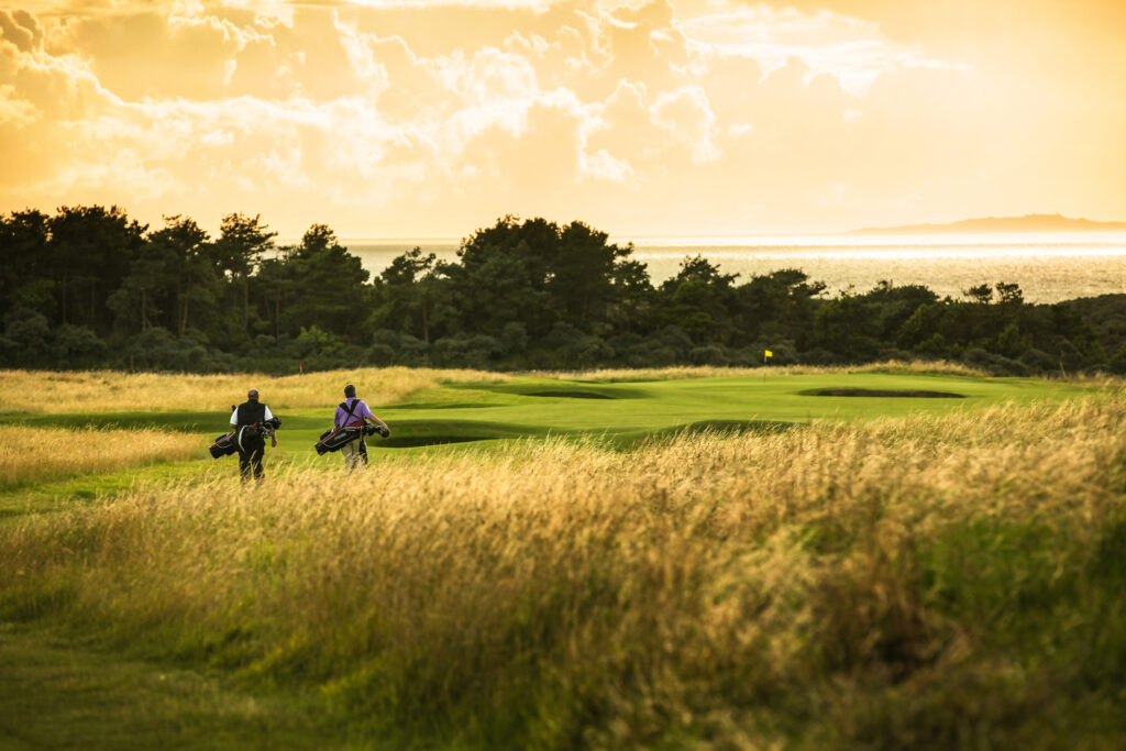 People playing golf at Muirfield with trees in distance