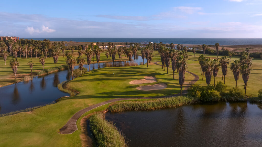 Lakes with beach in background surrounded by fairway with palm trees at Salgados Golf Course