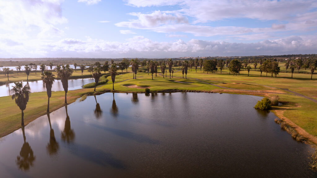 Lake with bunkers and fairway in background with palm trees at Salgados Golf Course