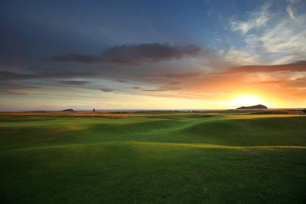 Hole with red flag at North Berwick Golf Club at sunset