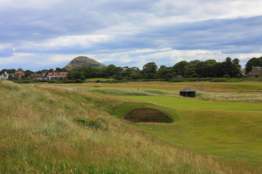 Bunkers on fairway at North Berwick Golf Club with trees and buildings in background