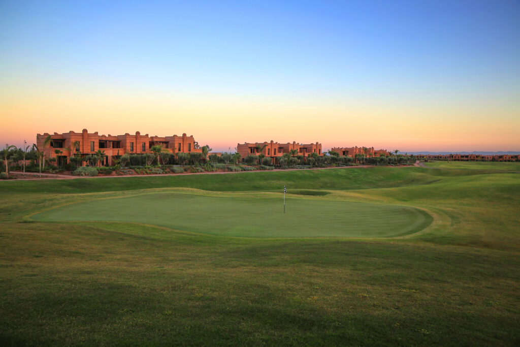 Hole with buildings in background at Palm Golf Ourika