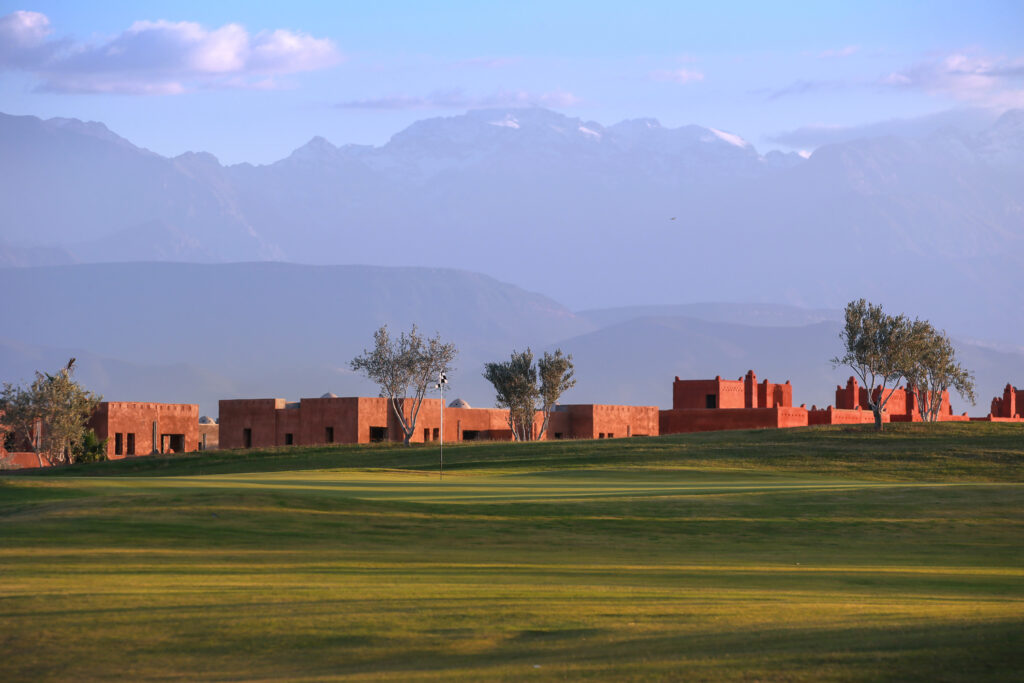 Hole with buildings in background at Palm Golf Ourika