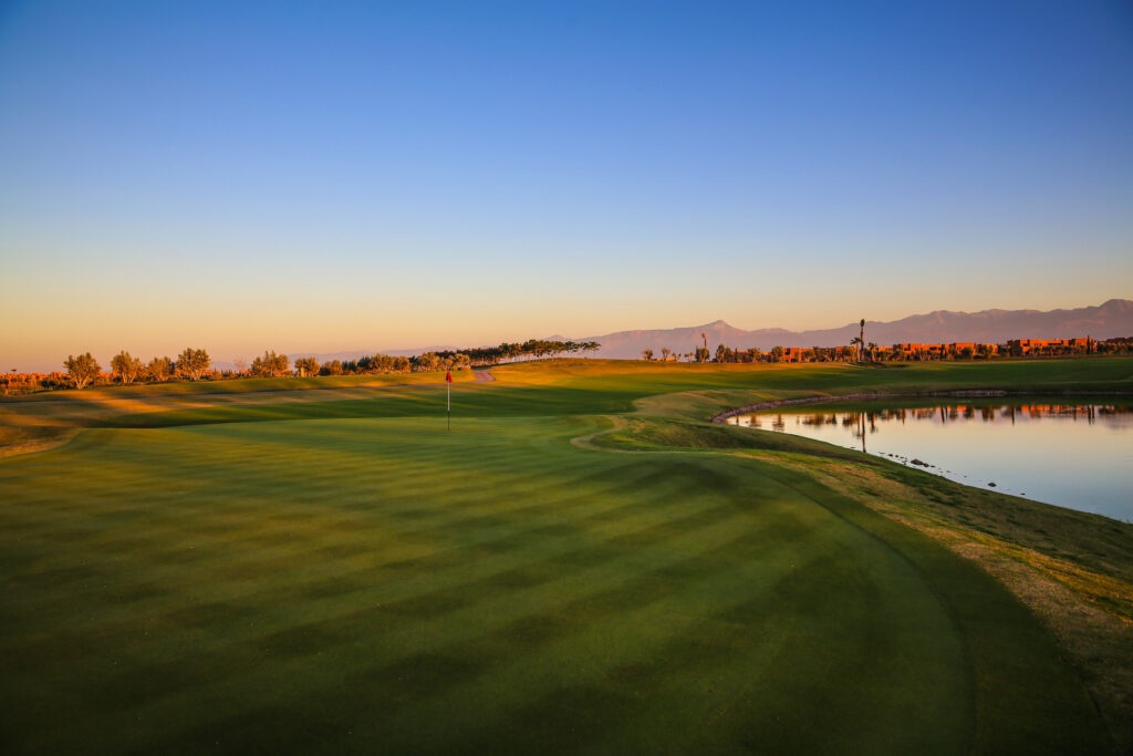 Hole with lake at Palm Golf Ourika with mountains in distance