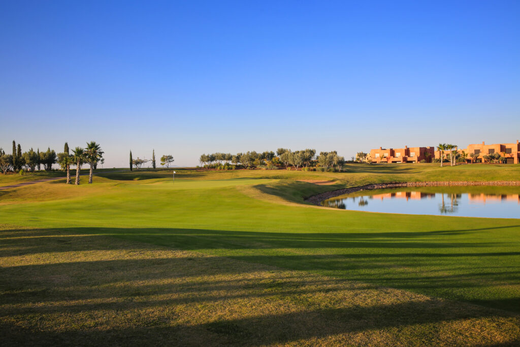 Hole with lake at Palm Golf Ourika with trees around