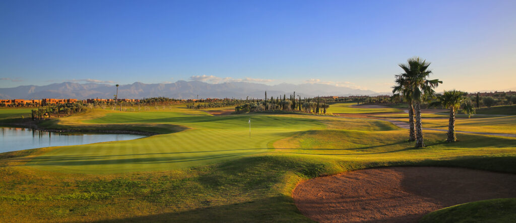 Hole with bunker at Palm Golf Ourika with lake and trees next to it