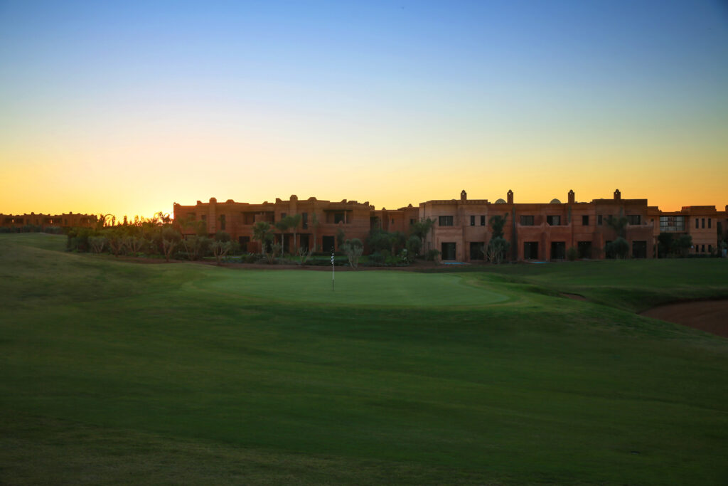 Hole with buildings in background at Palm Golf Ourika