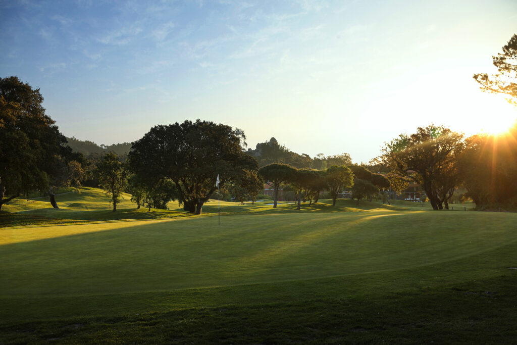 Hole surrounded by trees with sun shining down at Penha Longa Atlantic Course