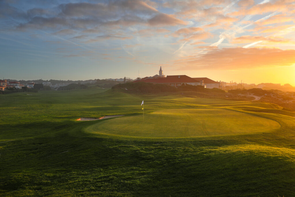 Sun set over a hole at Praia d'el Rey Golf Course with building in background