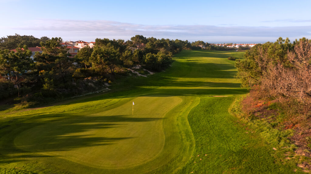 A green with a white flag with trees around at Praia d'el Rey Golf Course